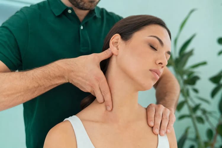 Close-up de um quiroprata manipulando a coluna cervical de um paciente sentado em uma cadeira especializada, com as mãos do terapeuta em ação.